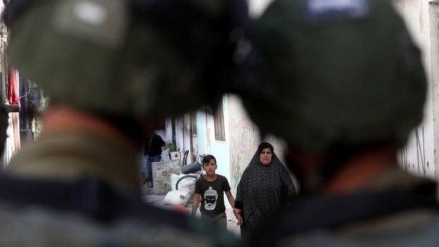 Palestinos andam em Hebrom observados por soldados israelenses