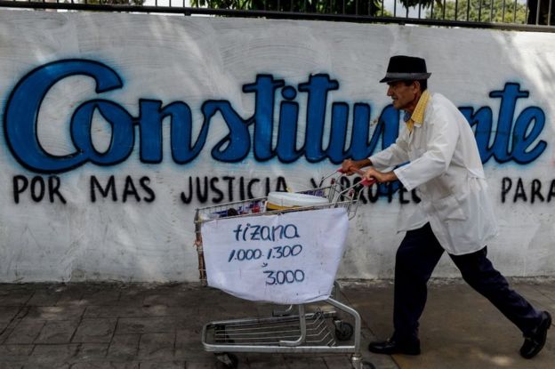 Un hombre pasa con su carro de supermercado frente a una pintada que hace referencia a las elecciones para una Asamblea Constituyente en Venezuela.