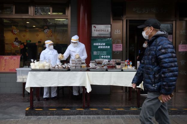 北京街头一家餐馆员工"全副武装"出售商品。