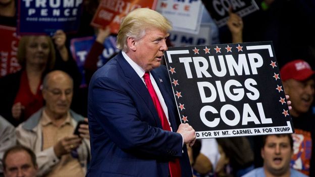 Donald Trump sostiene un cartel que dice 