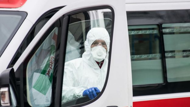 Un trabajador del hospital con equipo de protección se encuentra junto a una ambulancia en Padua, Italia