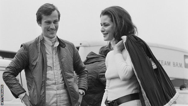 Formula 1 driver Mike Beuttler (left) talks to his companion Anne Ries de Loen (right) stood beside a car at Brands Hatch