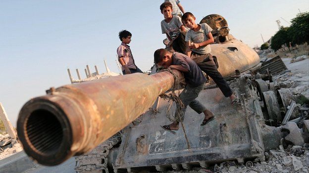 Children in Syria playing by a destroyed tank