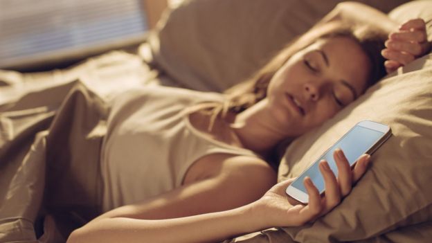 Mujer durmiendo con celular.