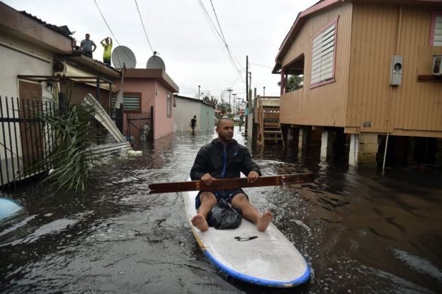 Un vecino navega por las calles inundadas con su tabla en Puerto Rico.