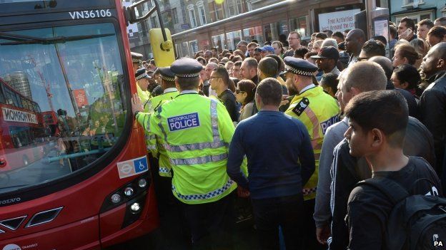 Police helping huge crowds of people to get on buses