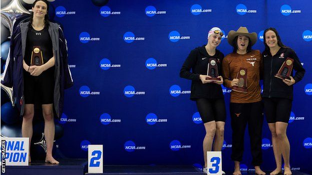 Transgender woman Lia Thomas (L) of the University of Pennsylvania stands on the podium after winning the 500-yard freestyle as other medallists (L-R) Emma Weyant, Erica Sullivan and Brooke Forde pose for a photo