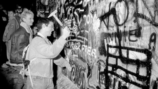 رجل يحطم جزءا من جدار برلين