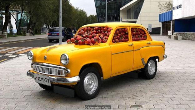 Carro amarelo cheio de maçãs em Almaty