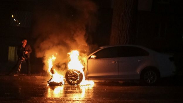 A man extinguishes a burning car of the embassy of Russia after a protest against the seizure by Russian special forces of three Ukrainian naval ships, which Russia blocked from passing through the Kerch Strait into the Sea of Azov in the Black Sea,