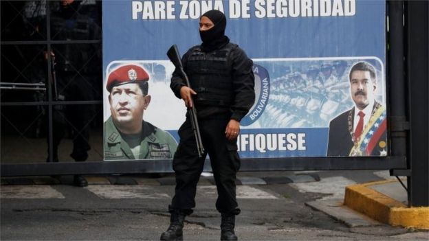 Members of the Bolivarian National Intelligence Service (SEBIN) stand guard next to a banner with the images of Venezuela's President Nicolas Maduro and Venezuela's late President Hugo Chavez, outside a detention centre, where a riot occurred, according to relatives, in Caracas, Venezuela May 16, 2018.