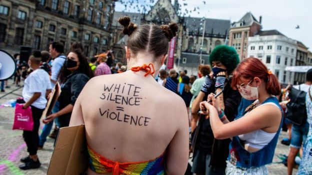"O silêncio dos brancos é violência", diz mensagem nas costas de uma manifestante branca