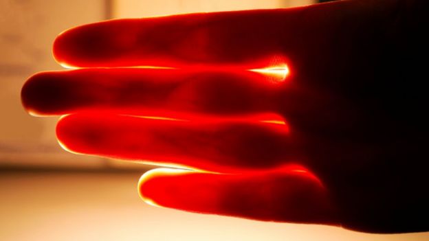 Red light shining through a person' hand