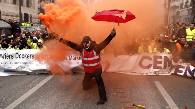 A protester holds a smoke torch during a demonstration against pension reforms in Marseille, France, 5 December 2019