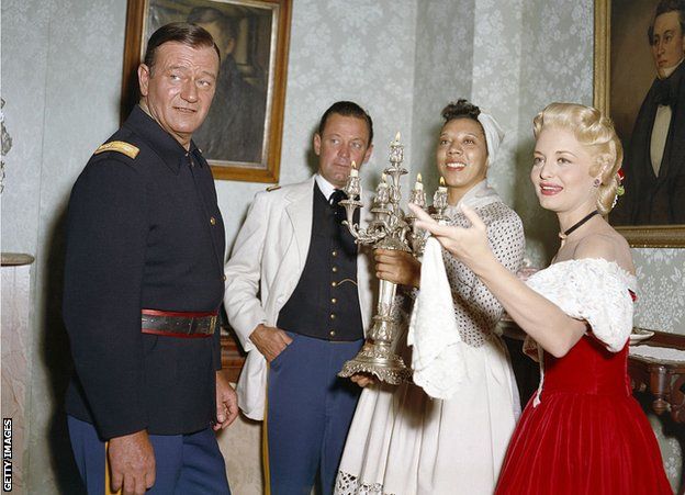 American actors John Wayne, William Holden, Althea Gibson and Constance Towers on the set of The Horse Soldier, directed by John Ford