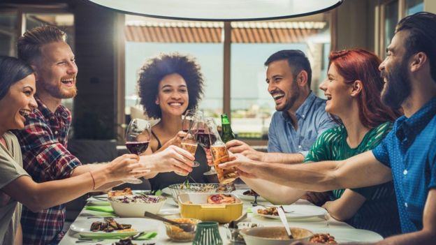 Un grupo de amigos brindando en una mesa.