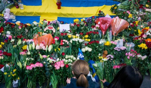 Women lay flowers on April 9, 2017 at a makeshift memorial near the point where a truck drove into a department store in Stockholm, Sweden