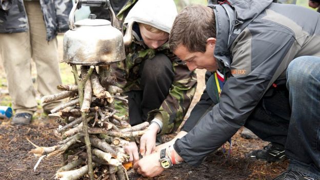 Chief scout Bear Grylls helping youngsters with lighting a fire