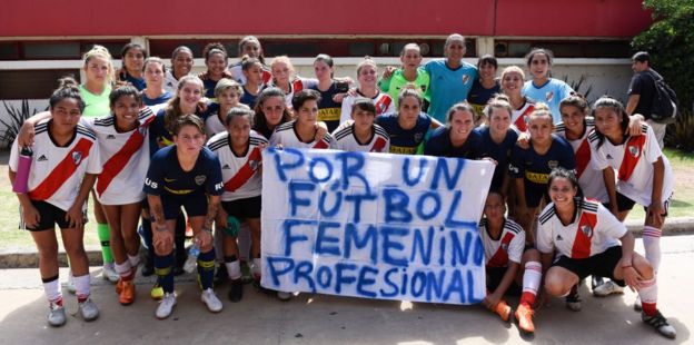Jugadores de Boca Juniors y River Plate posan con una pancarta en favor del fútbol profesional femenino.