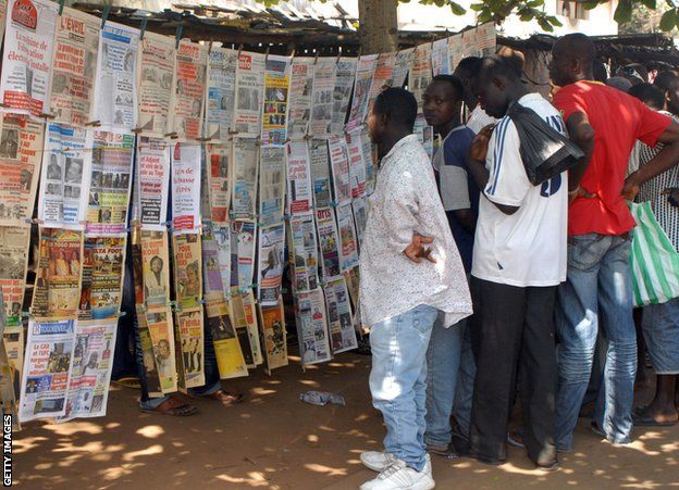Residents of Togo's capital Lome read through newspaper reports of the attack