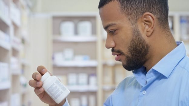 A man looking at a pill bottle in a pharmacy