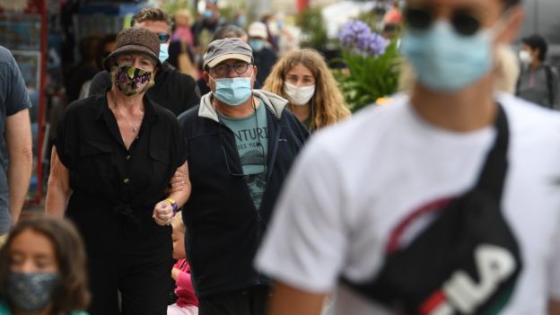 Personas caminando en la calle con mascarilla