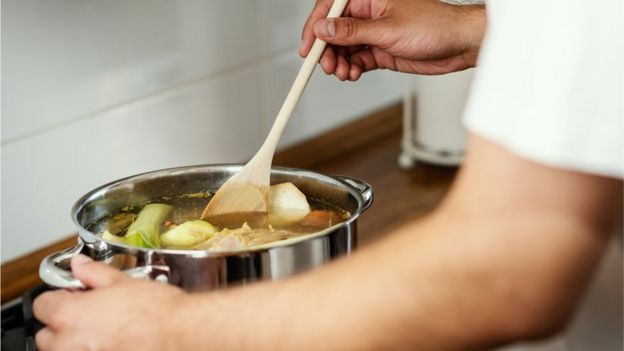 A man cooking a fragrant broth in a pot - stock photo
