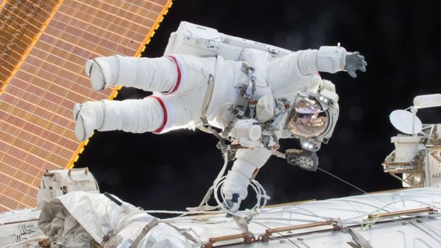 La fotografía del folleto muestra a Scott Kelly flotando afuera de la estación espacial