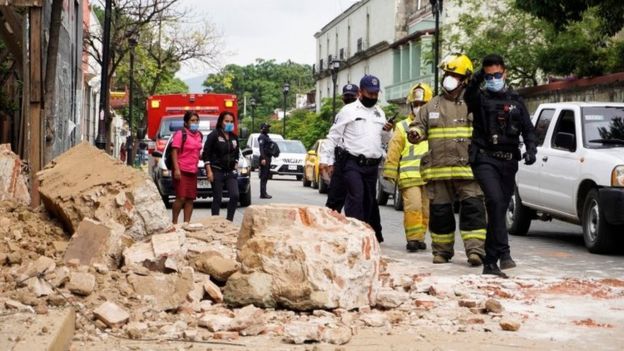 Members of the police and fire department observe the damage caused by a collapsed fence wall in Oaxaca, Mexico, 23 June 2020.