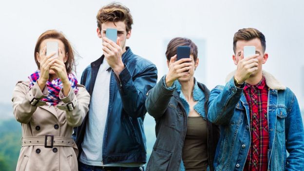 Jovens com celular na frente do rosto