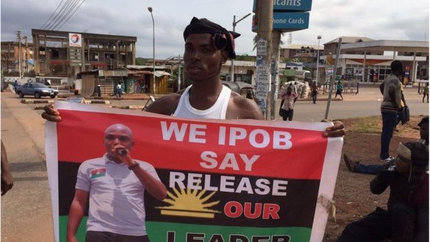 Hombre sostiene un cartel que pide la liberación de un preso en Nigeria.