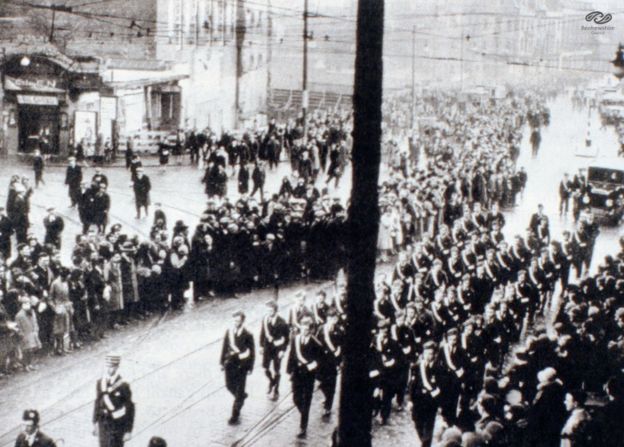 Grupo Boys Brigade marchaa em frente ao cinema no funeral das vítimas