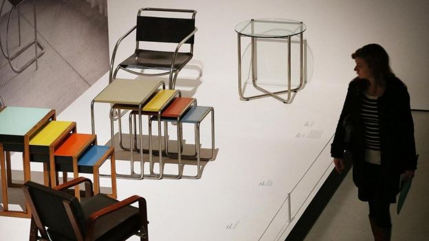 Visitante observa mesas e cadeiras expostas na exibição 