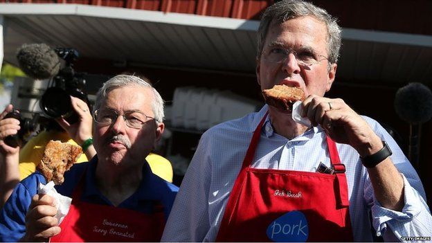 Republican presidential hopeful and former Florida Gov. Jeb Bush (R) and Iowa Gov. Terry Branstad eat a pork chop on a stick at the Iowa Pork Tent during the Iowa State Fair
