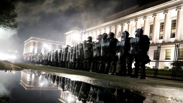 Riot police stand guard during a protest in Kenosha on 25 August