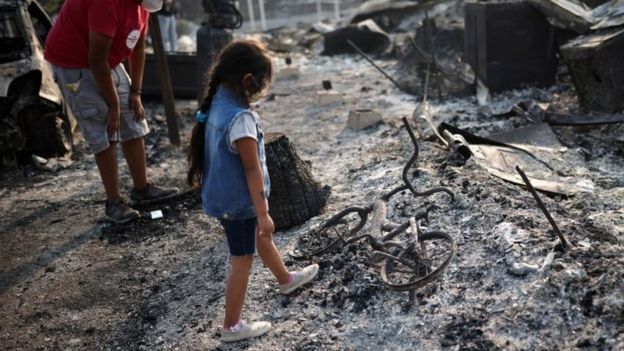 Una niña mira un bici quemada.