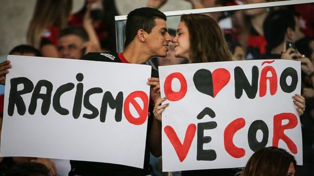 Dos jóvenes hinchas del equipo brasileño Flamengo sostienen carteles que dicen: 