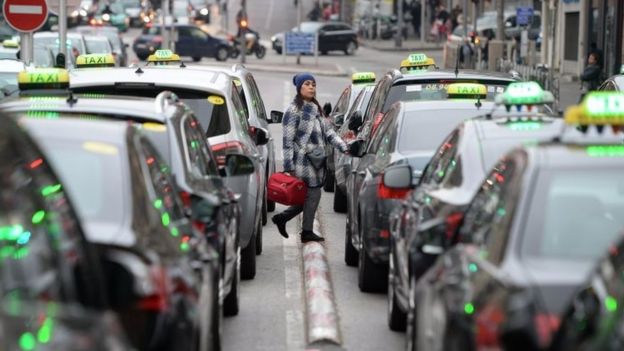 A woman walks past taxicabs parked at Castellane Square during a protest by taxi drivers against private hire services in Marseille, southern France (27 January 2016)