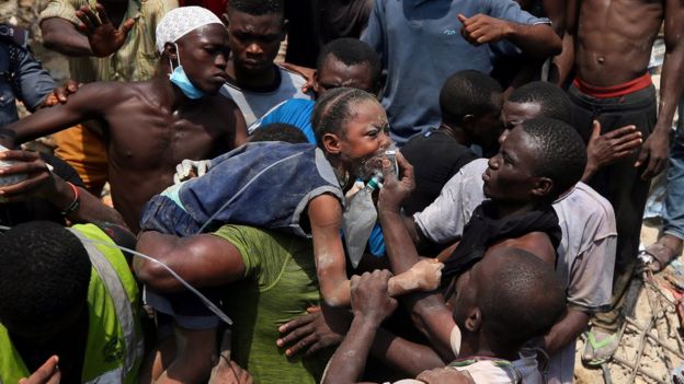 Rescue workers help carry a child at the site of a collapsed building containing a school in Nigeria's commercial capital of Lagos, Nigeria March 13, 2019