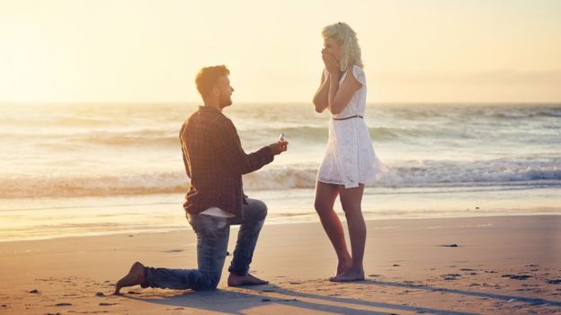 Un hombre pidiéndole matrimonio a una mujer en la playa