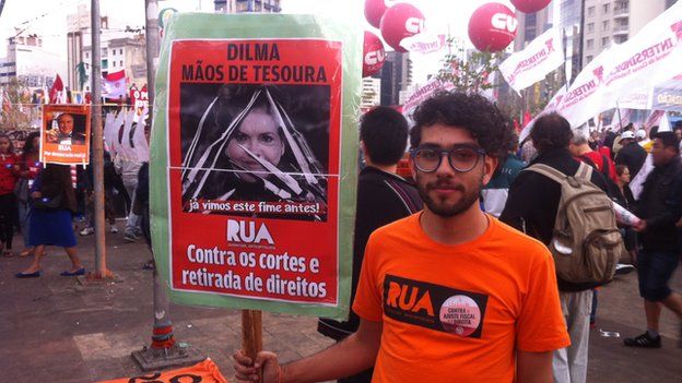 Protestor with a banner saying: “Dilma scissor hands – against cuts and removal of our rights"