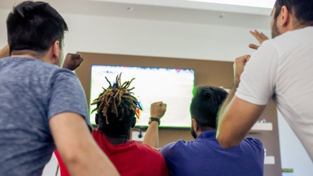 Amigos assistindo a partida na TV