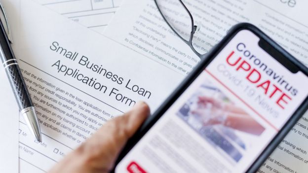 A small business loan application form and a phone showing updates on coronavirus