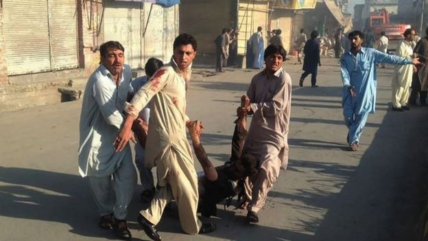 People in Parachinar carry an injured man after a twin blasts at the town's market