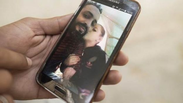 Uma mão segura um telefone com uma foto de Nidhal Gharibi