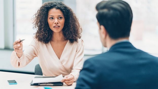 Hombre y mujer en oficina conversando.