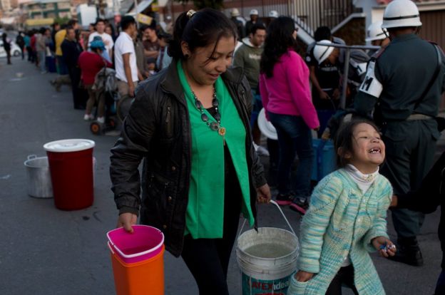 Mujer carga baldes con agua