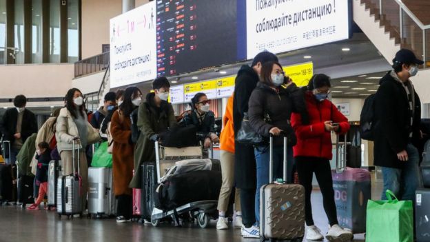 Gente con maletas haciendo cola en un aeropuerto.