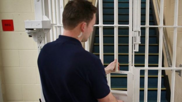 A prison officer locking a gate