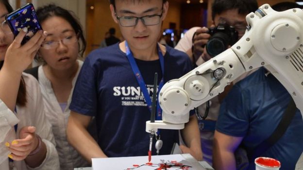Jovens observam robô pintando durante a abertura do 3º World Intelligence Congress em Tianjin, na China.